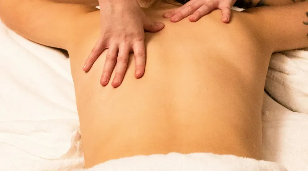 Mains effectuant un massage du dos sur une personne allongée